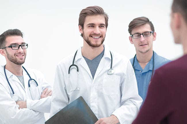 krankenzusatzversicherung Gruppe junger Ärzte gratuliert Patient zur Entlassung